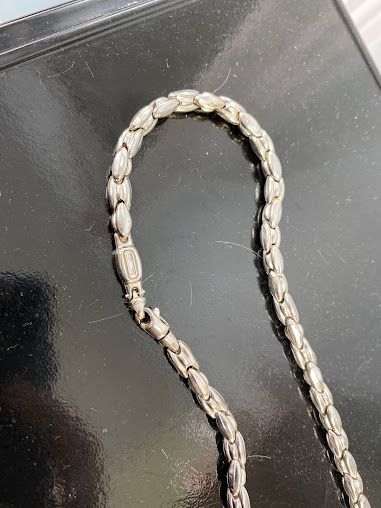 A close up of a silver chain on a black surface.