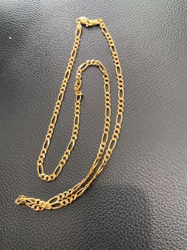 A gold chain is laying on a black surface.