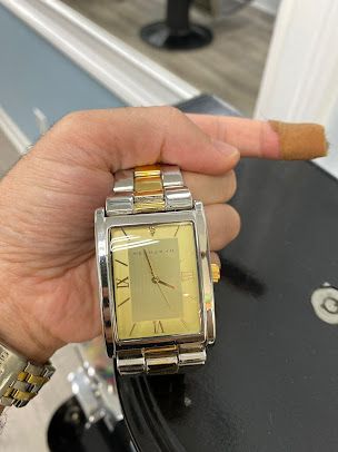 A person is holding a watch in their hand and pointing at it.