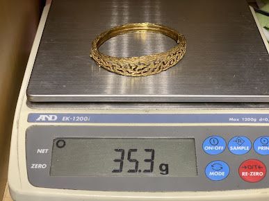 A gold bangle is sitting on top of a digital scale.