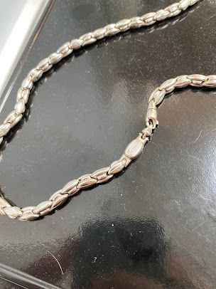 A close up of a silver chain on a black surface.