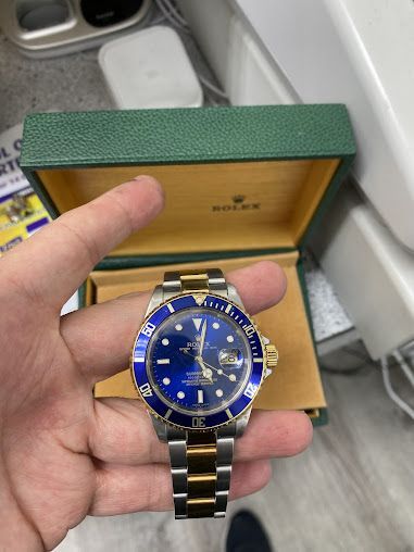 A person is holding a rolex watch in their hand.