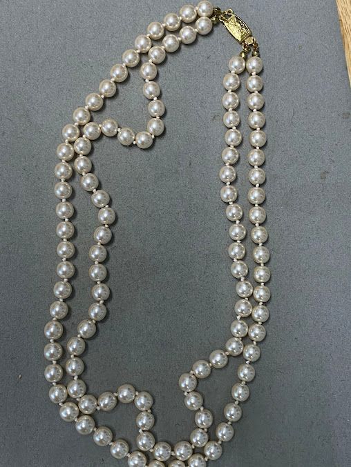 A close up of a pearl necklace with a gold clasp