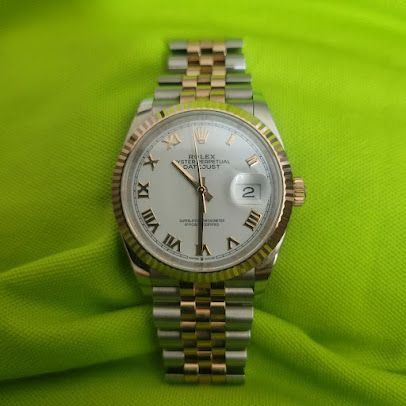 A silver and gold rolex watch is sitting on a green cloth.