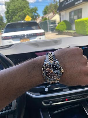A man is driving a car and wearing a watch on his wrist.