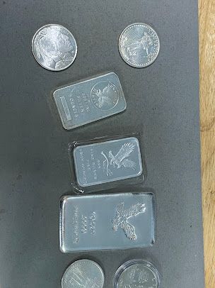A bunch of silver coins and bars are sitting on a table.