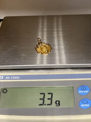 A small piece of gold is being weighed on a scale.