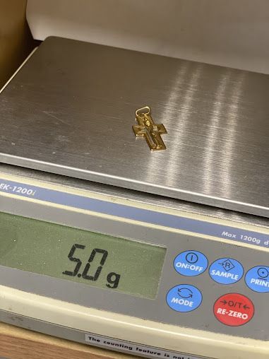 A gold cross is sitting on top of a digital scale.