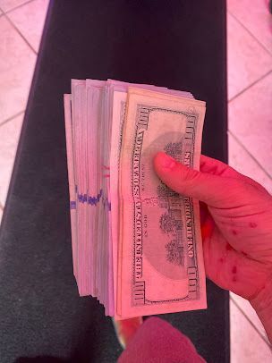 A person is holding a stack of money in their hand.