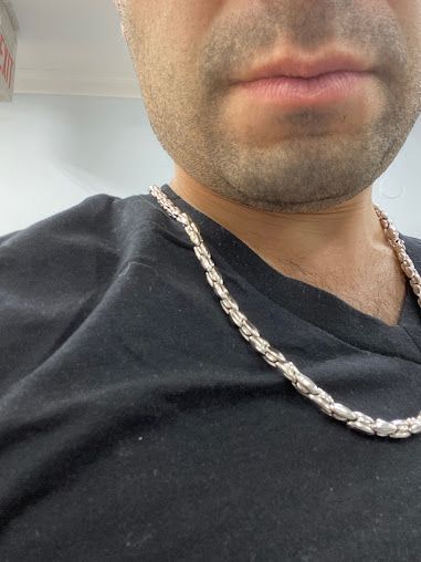 A man wearing a black shirt and a silver chain around his neck.