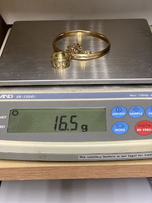 A gold bracelet and ring are being weighed on a scale.