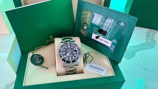A rolex watch is sitting in a green box.