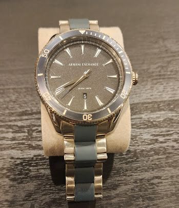 A armani exchange watch is sitting on a wooden table.