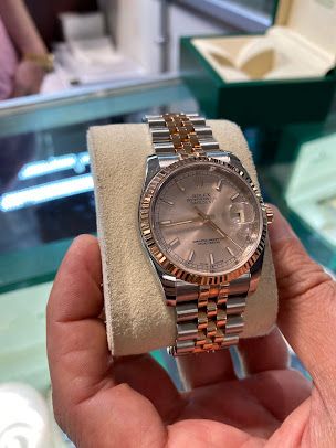 A person is holding a rolex watch in their hand.