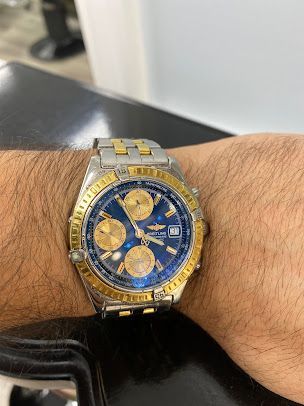 A man is wearing a breitling watch on his wrist.