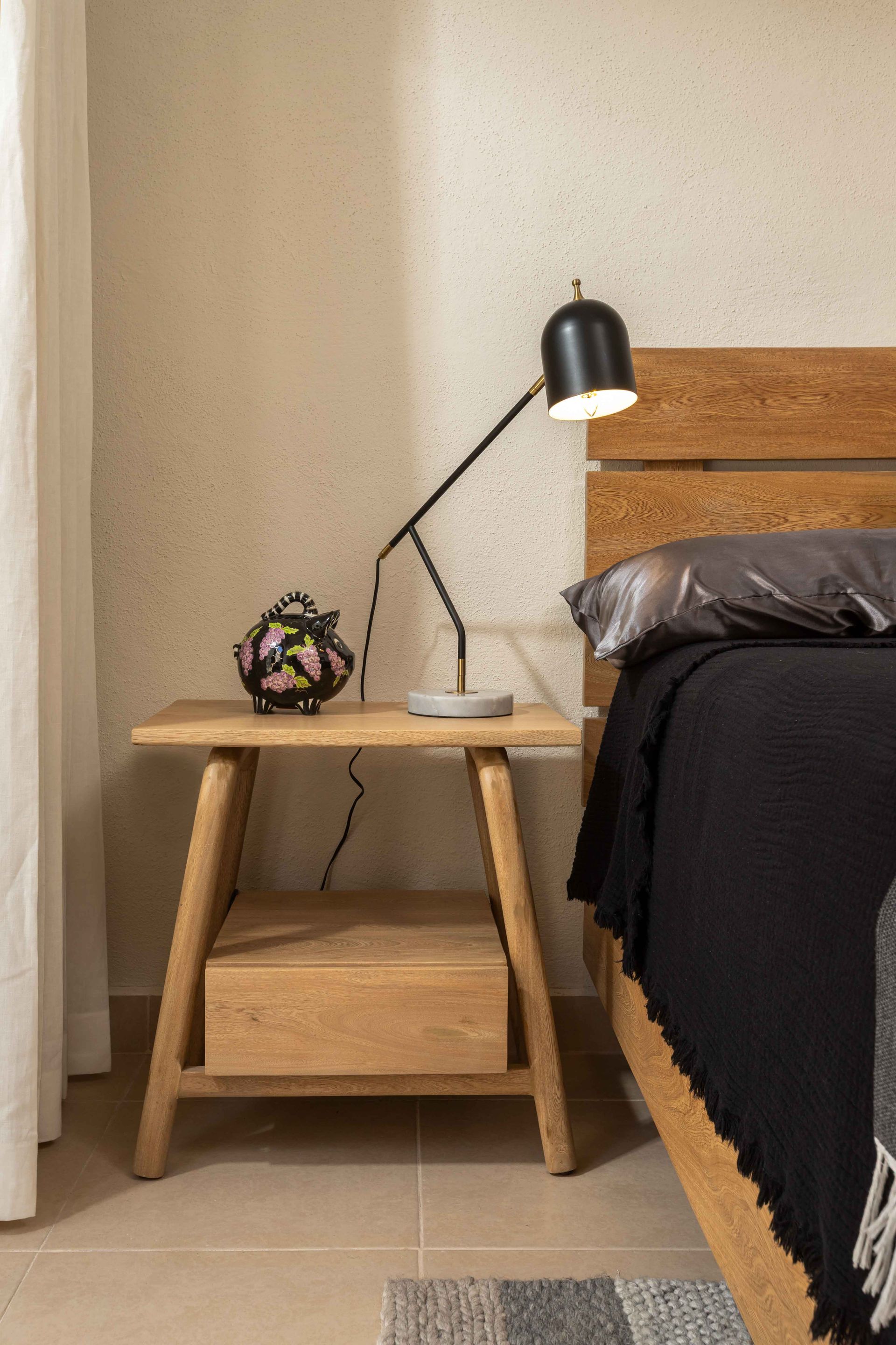 A bedroom with a bed , nightstand , lamp and nightstand.