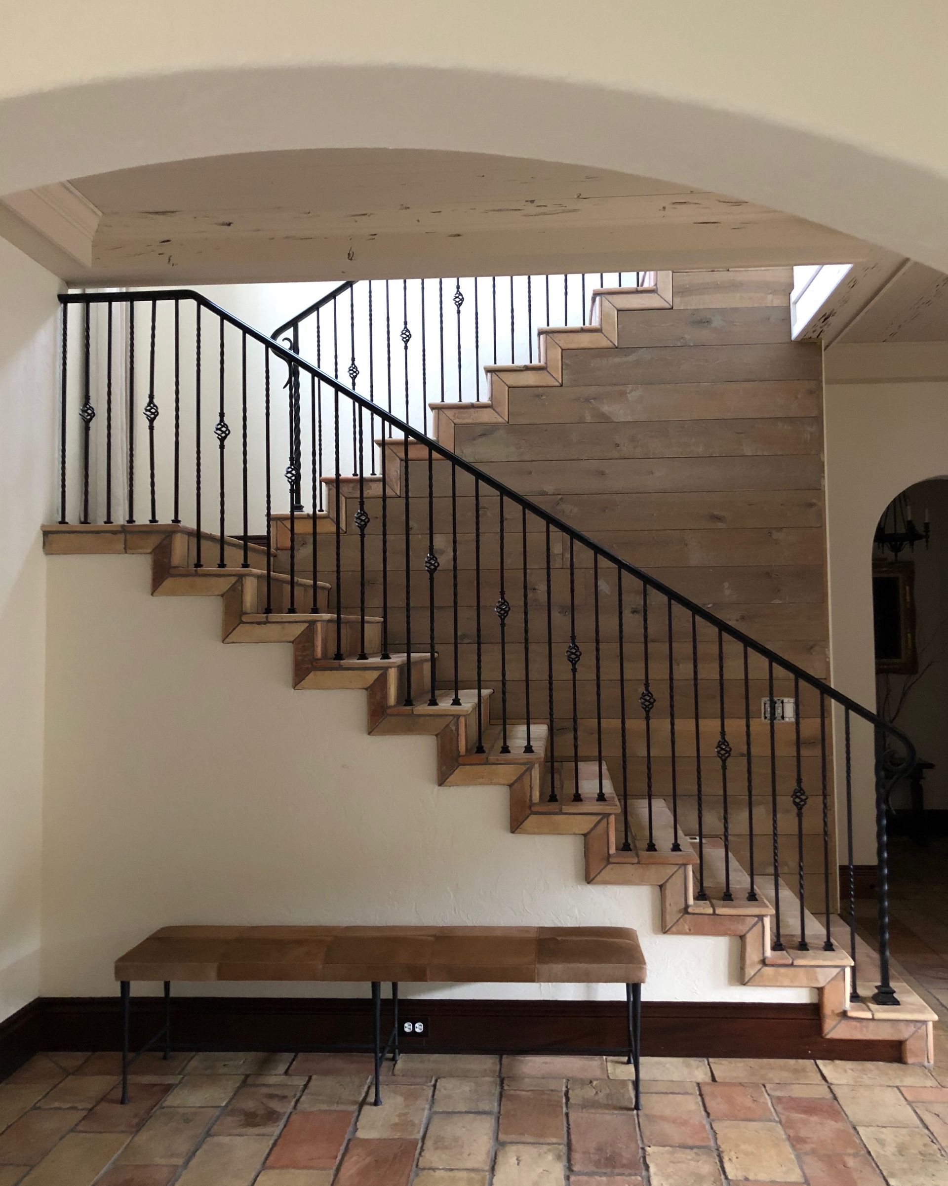 A wooden staircase with a metal railing in a hallway