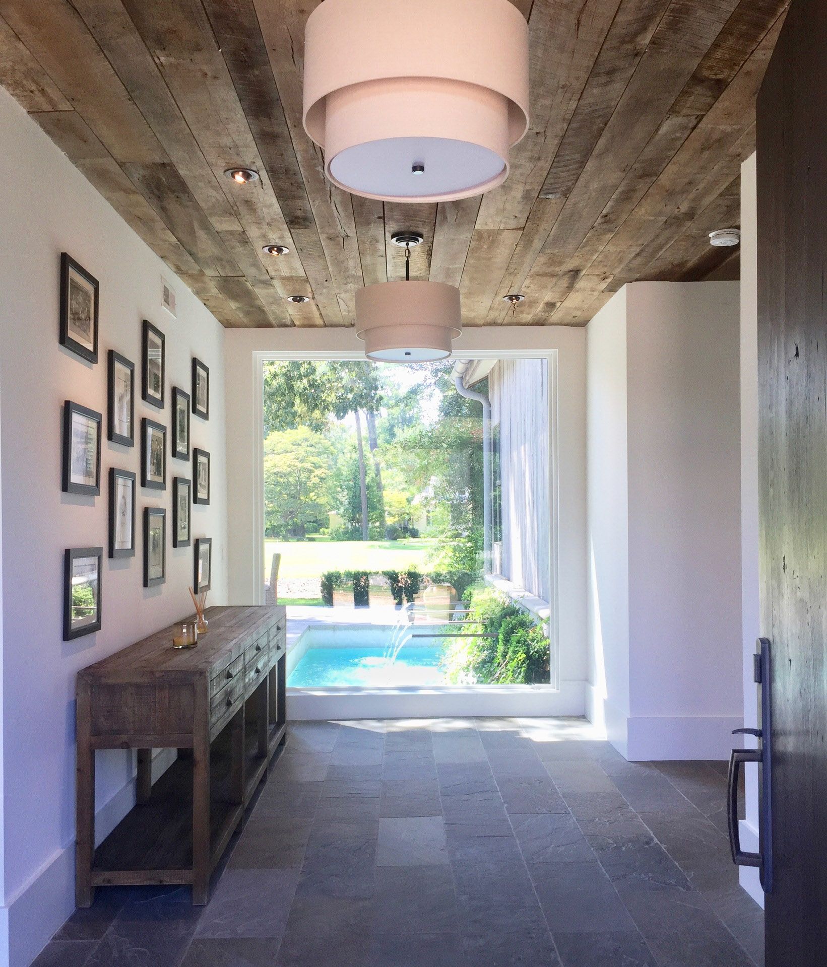 A hallway with a wooden ceiling leading to a pool
