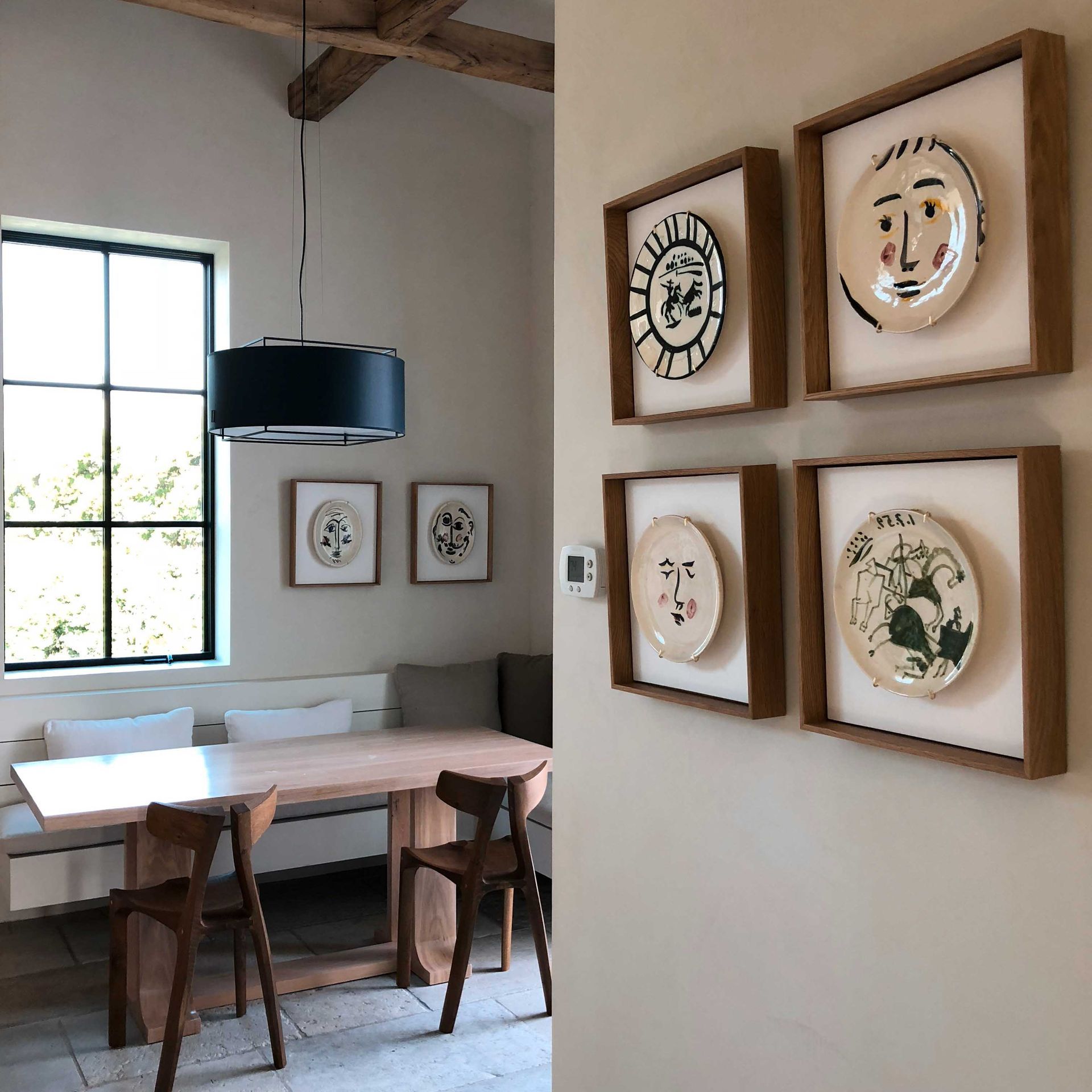 A dining room with a table and chairs and plates on the wall