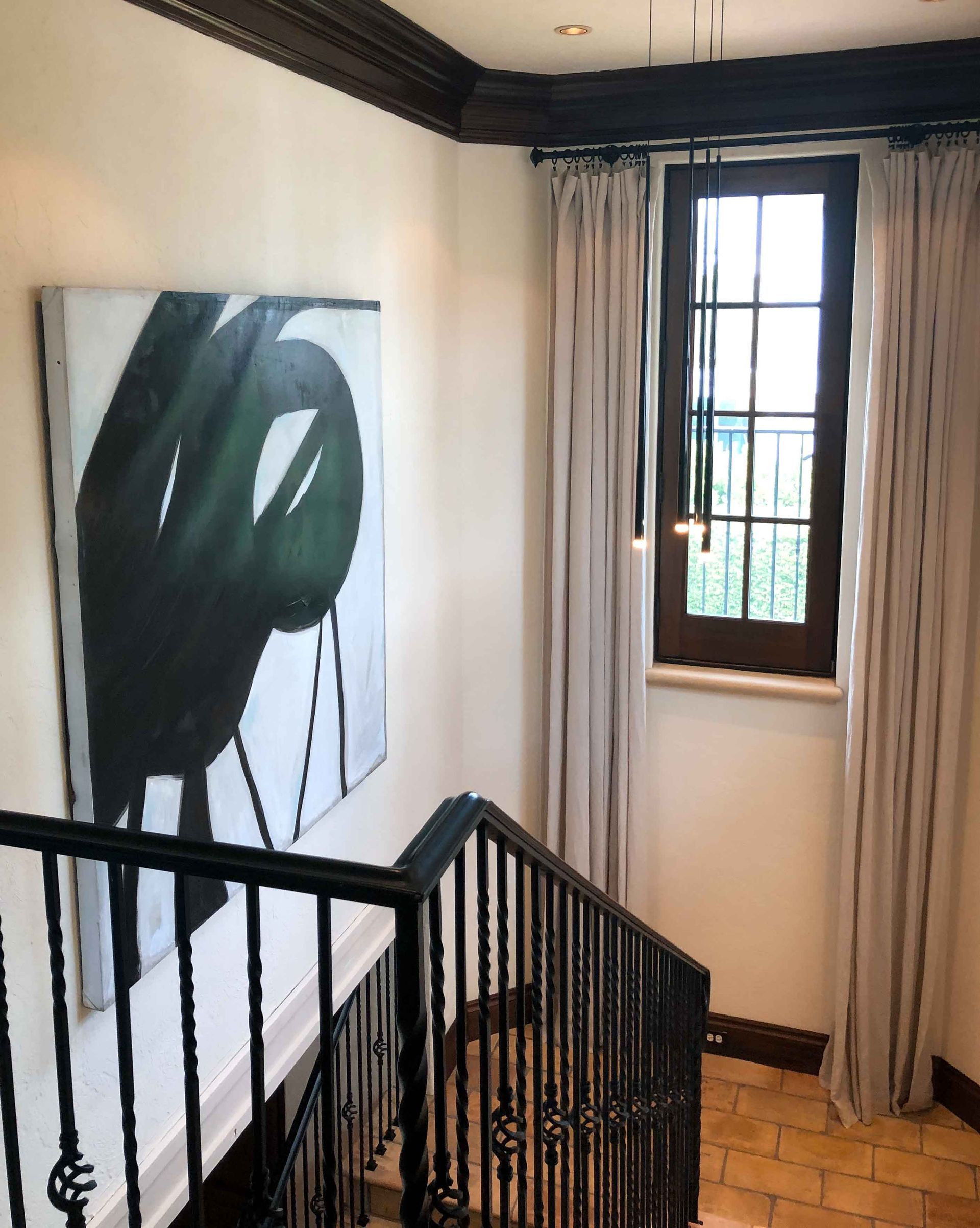 A staircase with a painting on the wall and a window