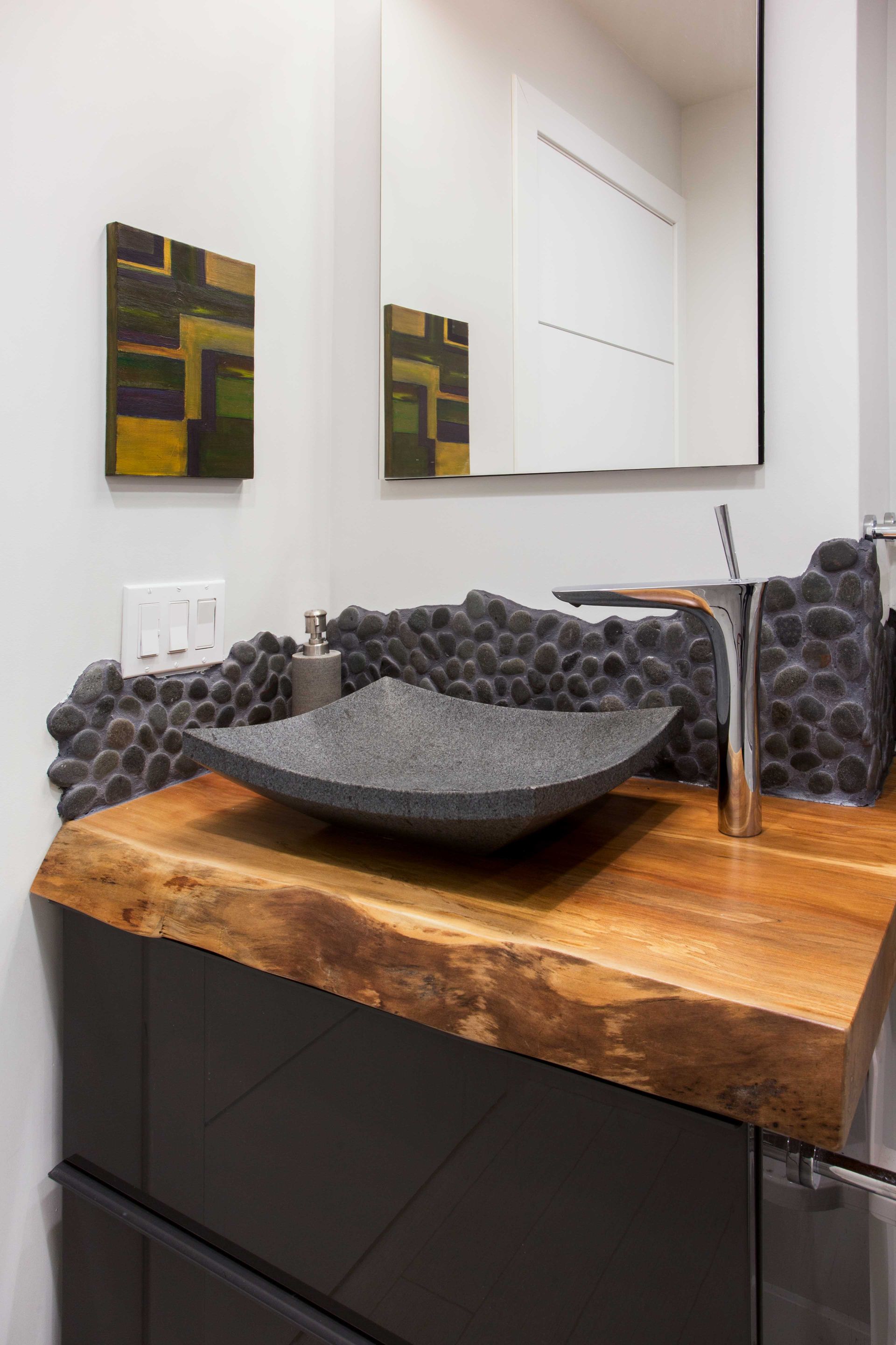 A bathroom sink with a wooden counter top and a mirror.