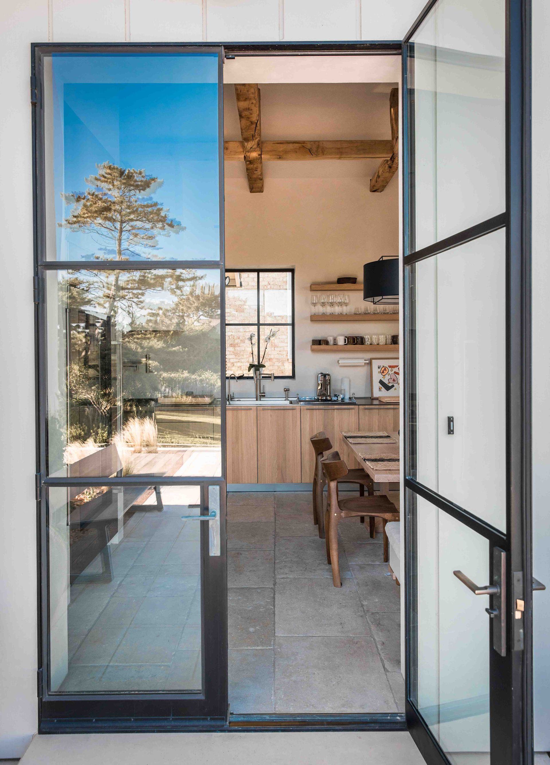 A glass door is open to a kitchen and dining room.