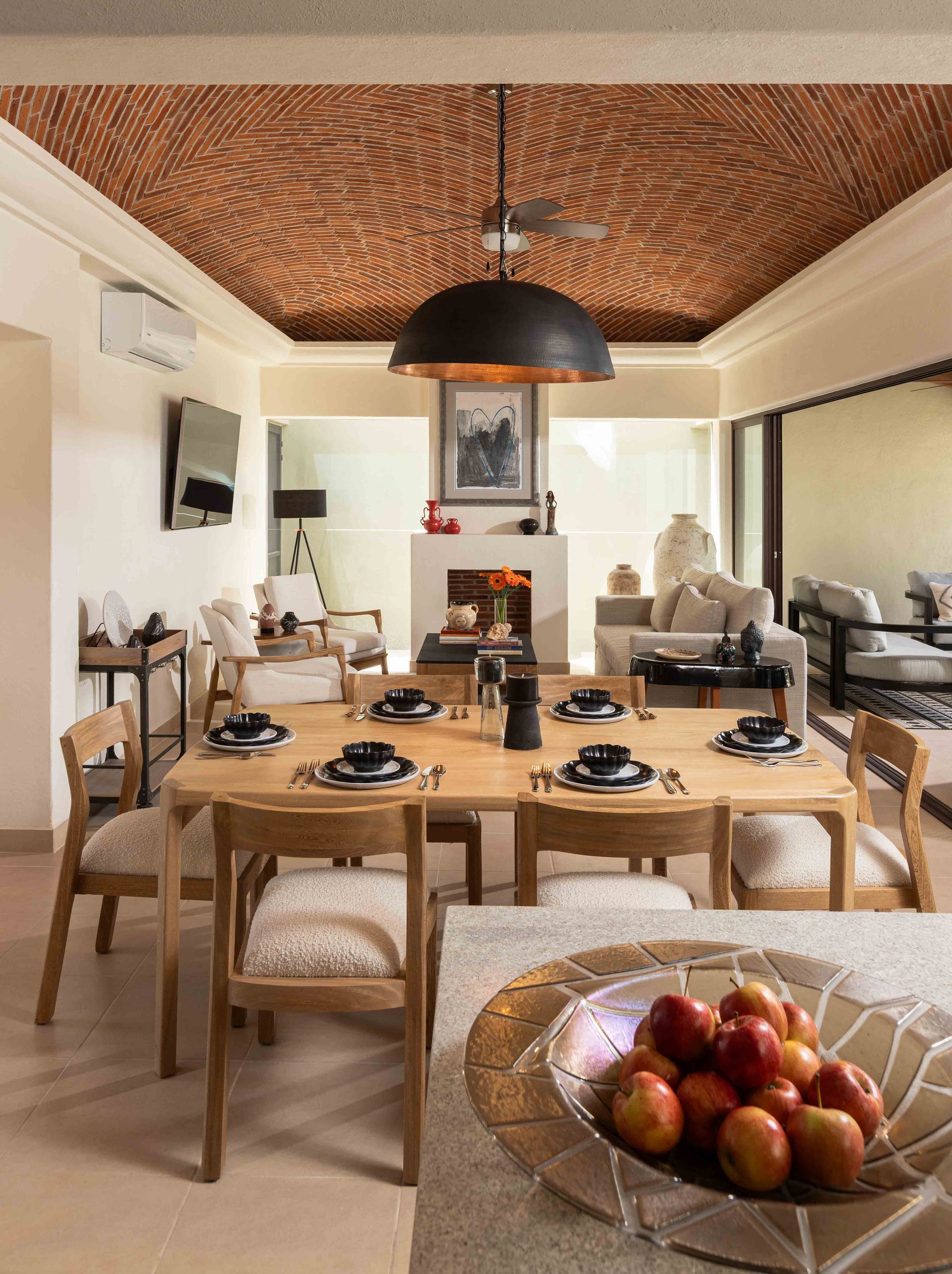 A dining room with a table and chairs and a bowl of fruit on the table.