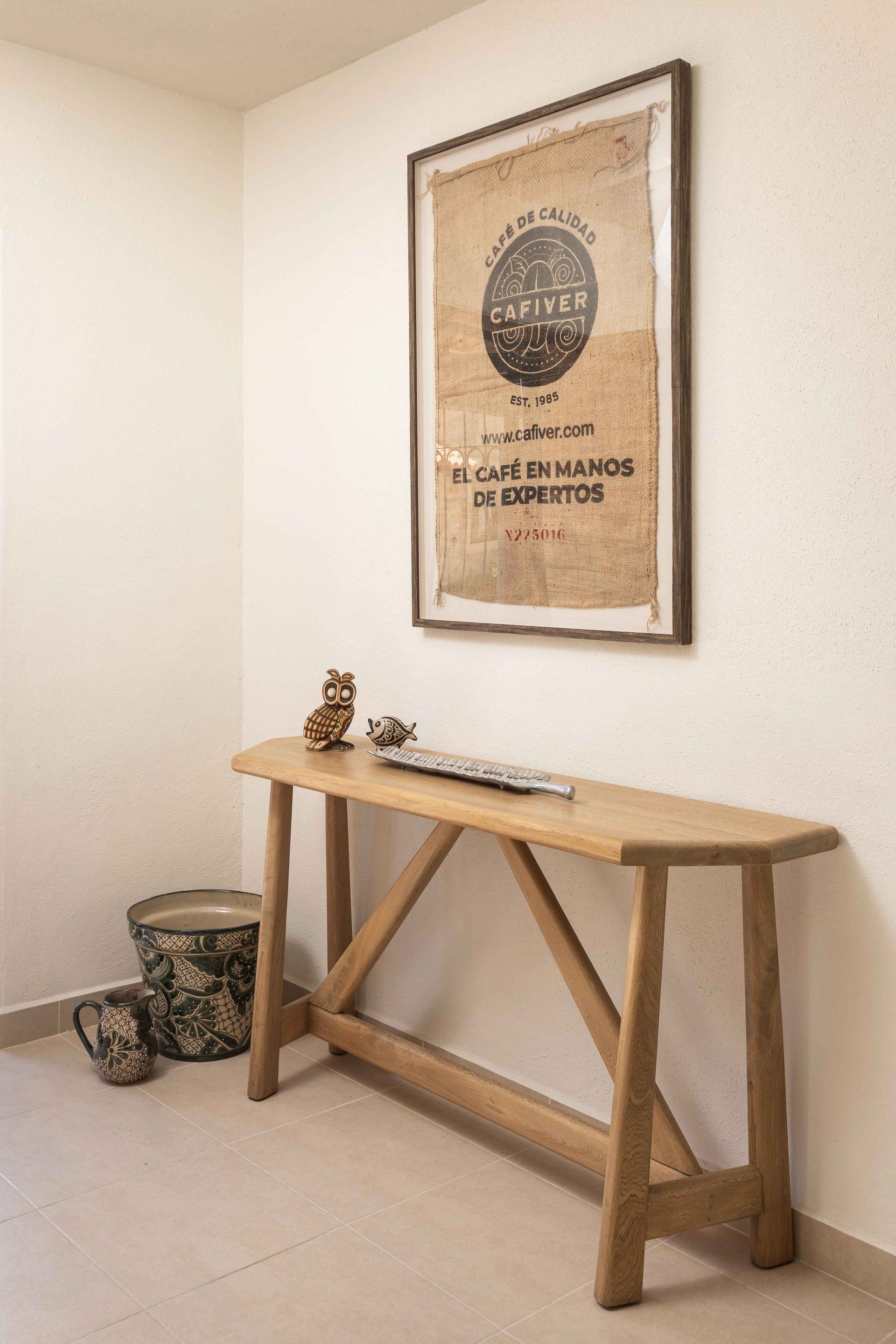 A wooden table with a picture on the wall above it.
