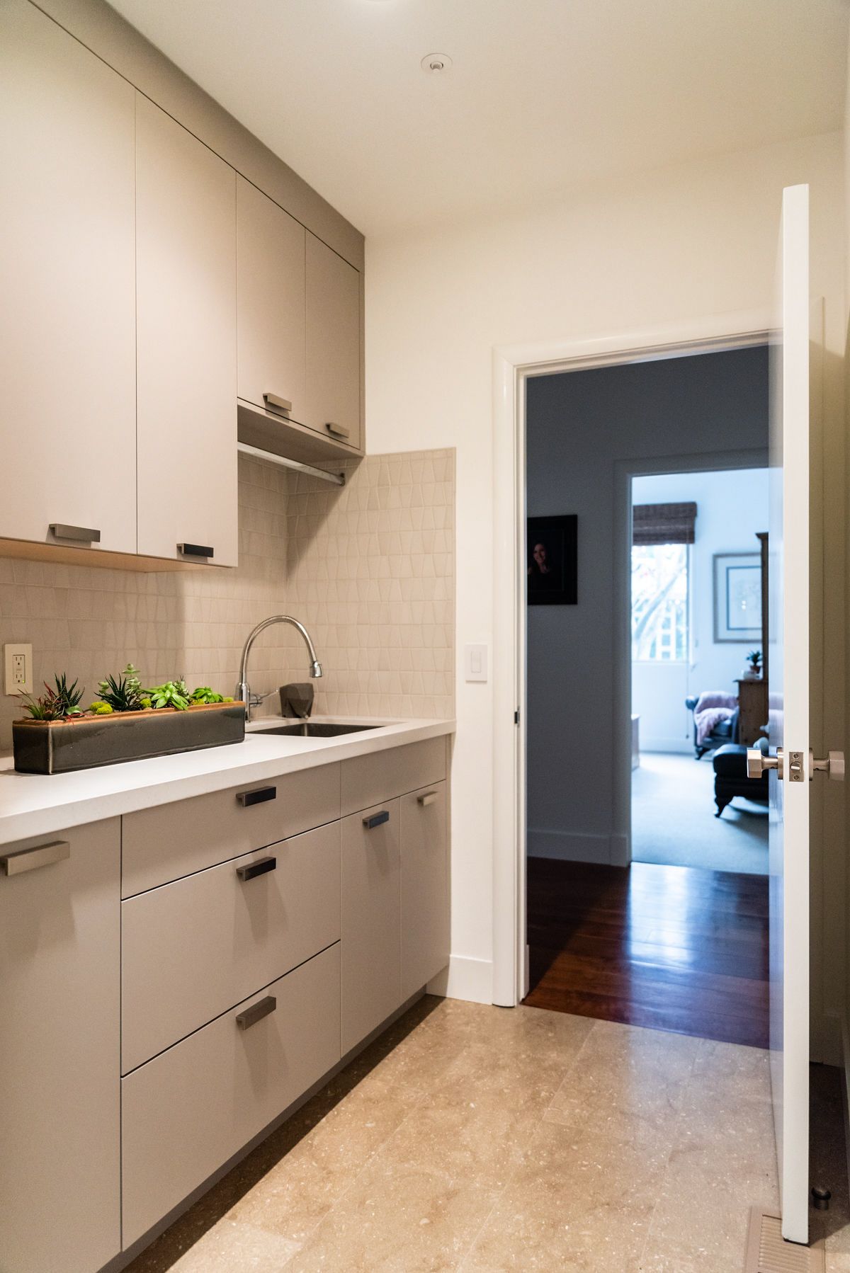 A kitchen with a sink , cabinets and a door leading to a living room