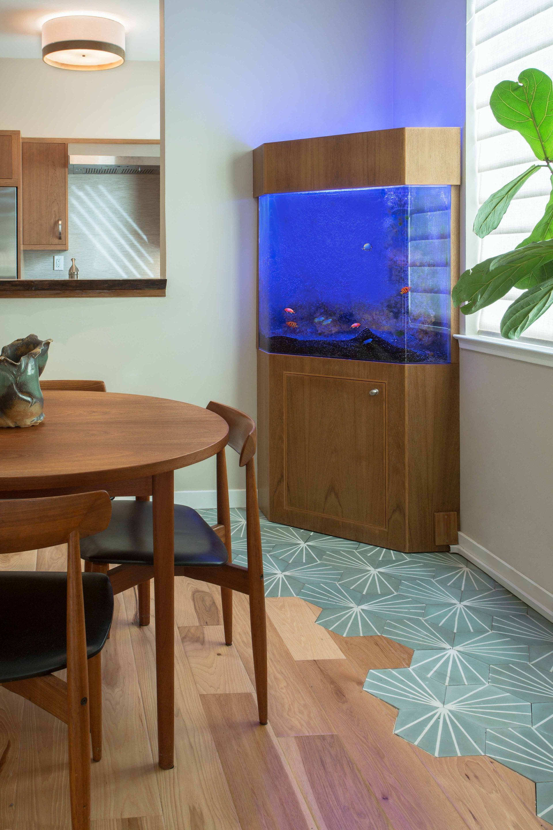 A dining room with a table and chairs and an aquarium in the corner.
