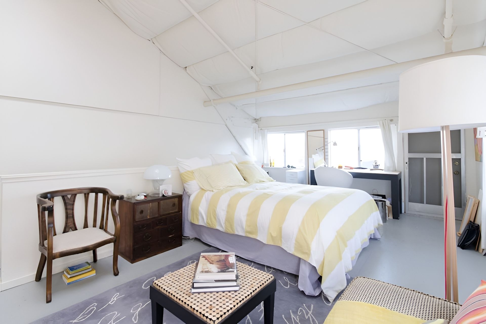A bedroom with a bed , chairs , a table and a lamp.