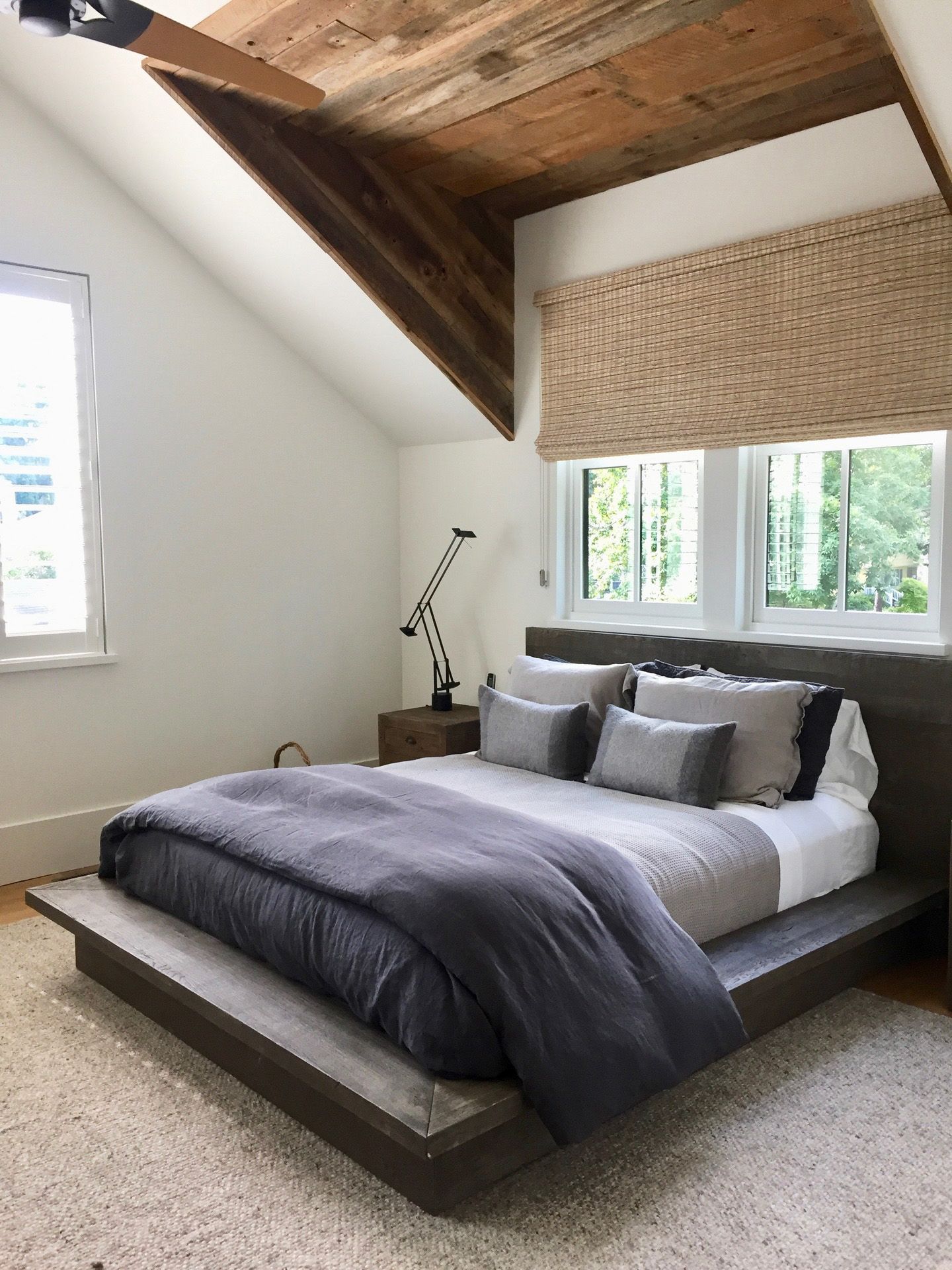 A bedroom with a large bed and a wooden ceiling.