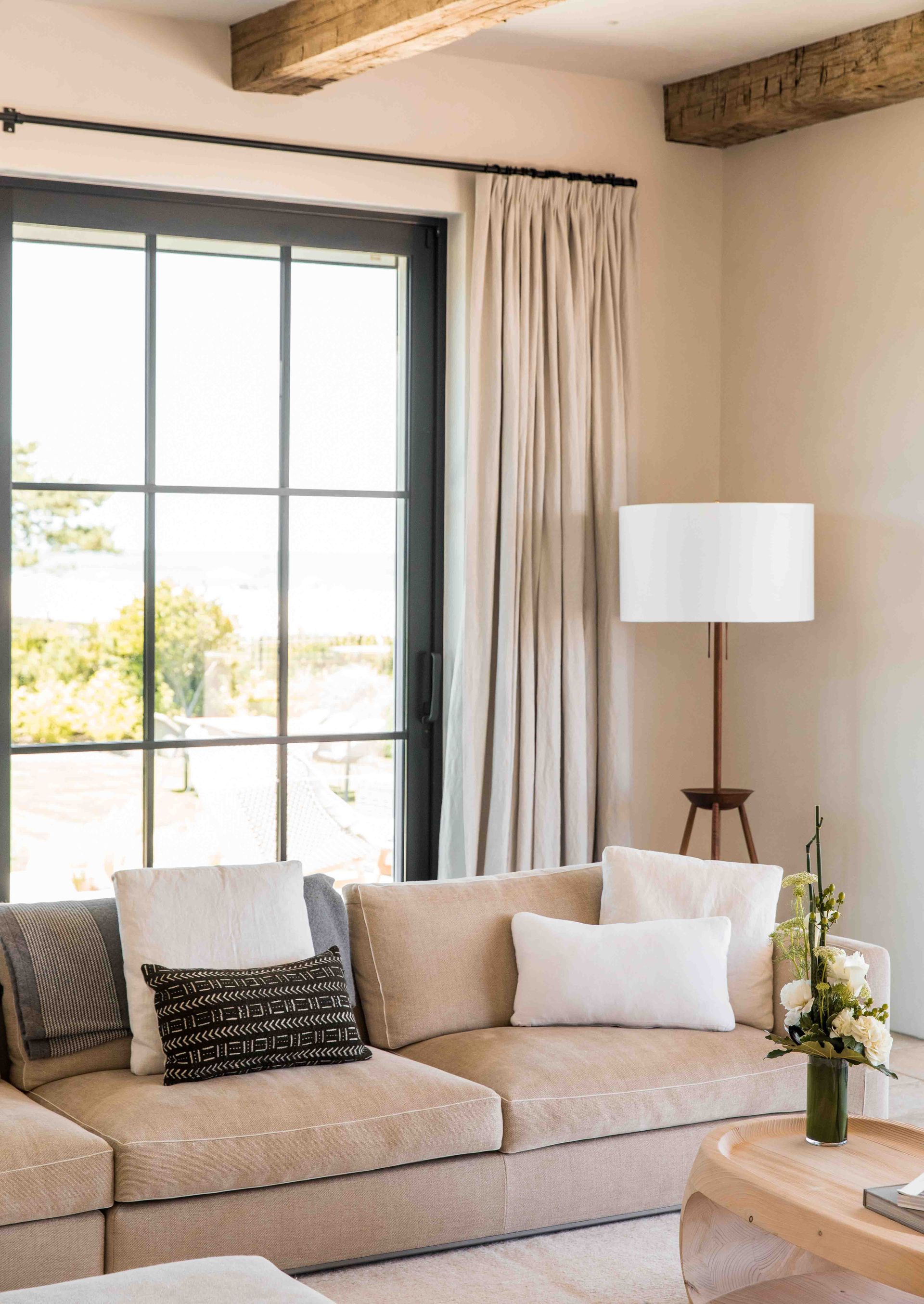 A living room with a couch , table , lamp and window.