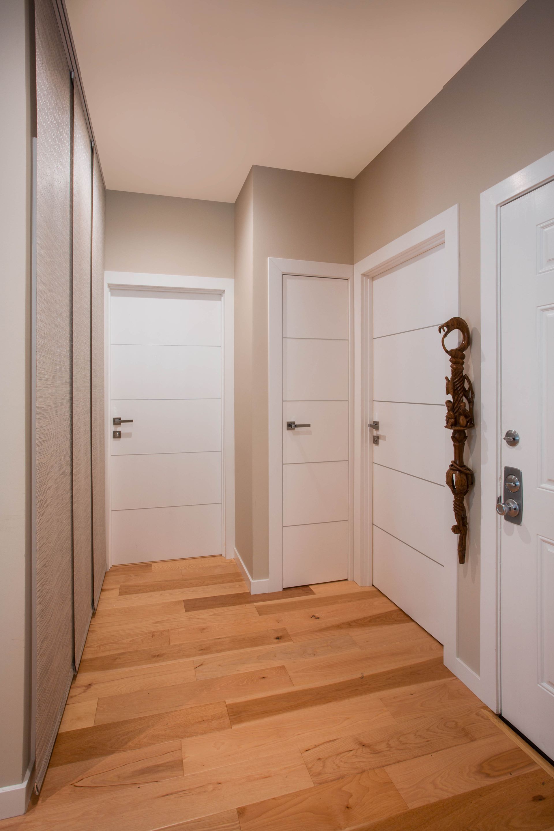 A hallway with wooden floors and white doors