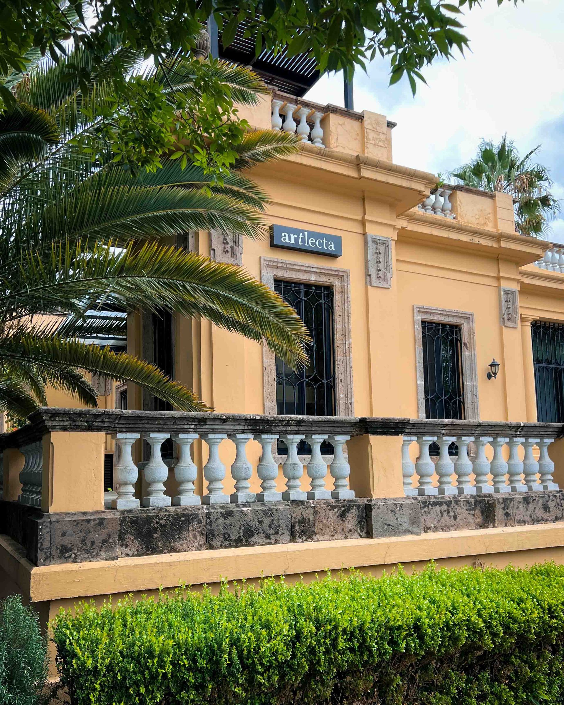 A large yellow building with a balcony and a fence in front of it.