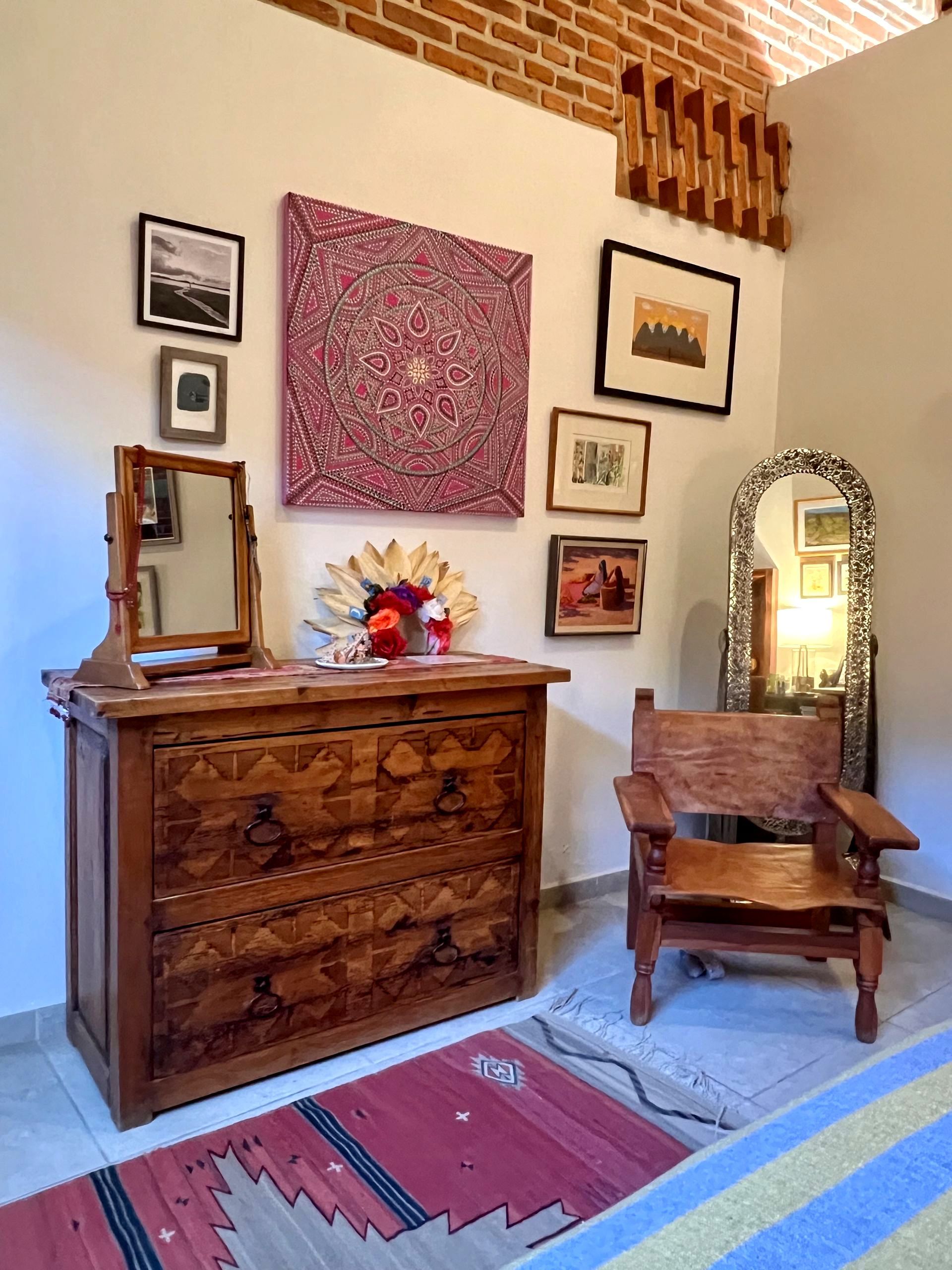 A bedroom with a dresser a chair and a mirror