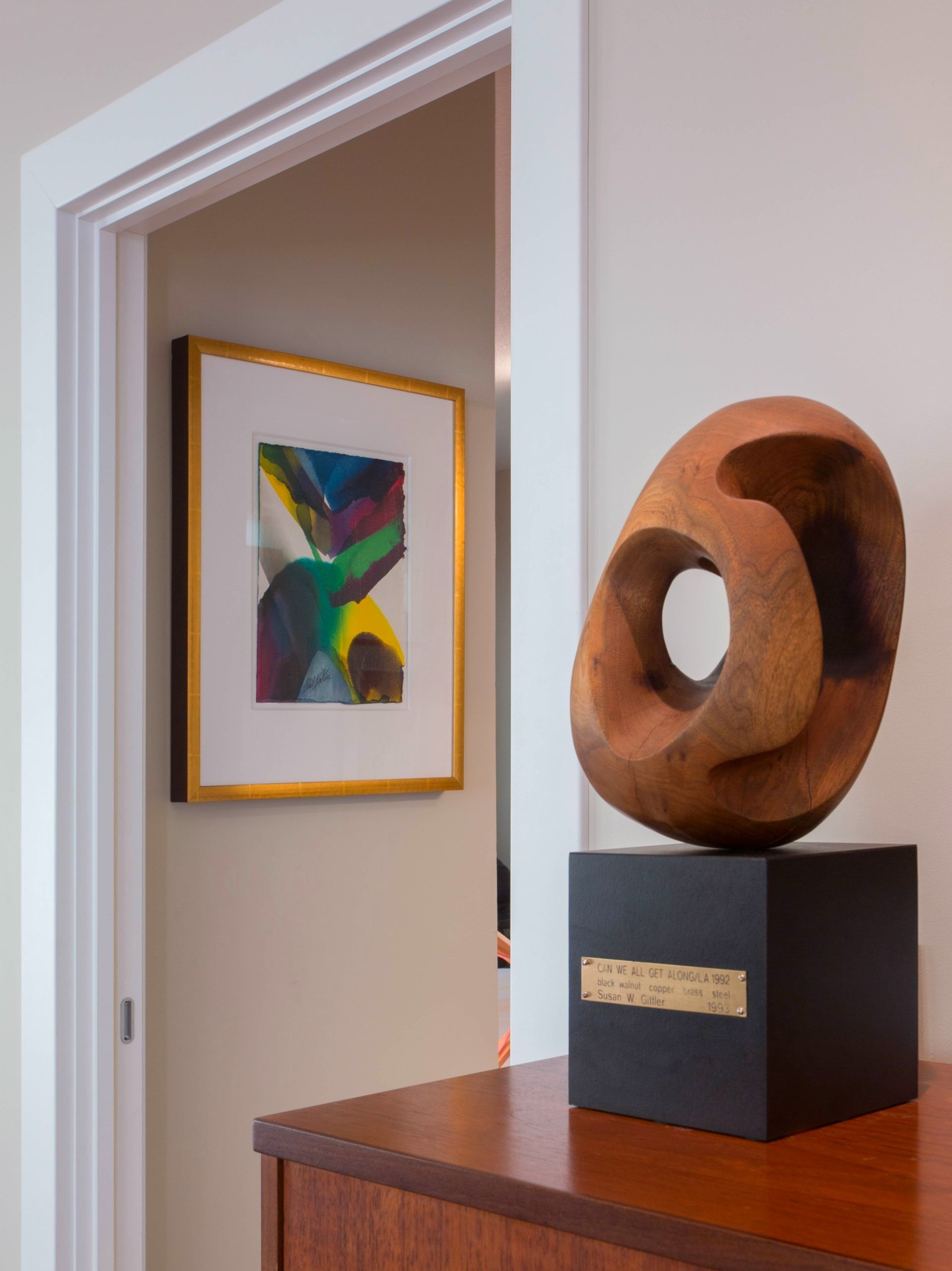 A wooden sculpture sits on a wooden dresser in front of a door