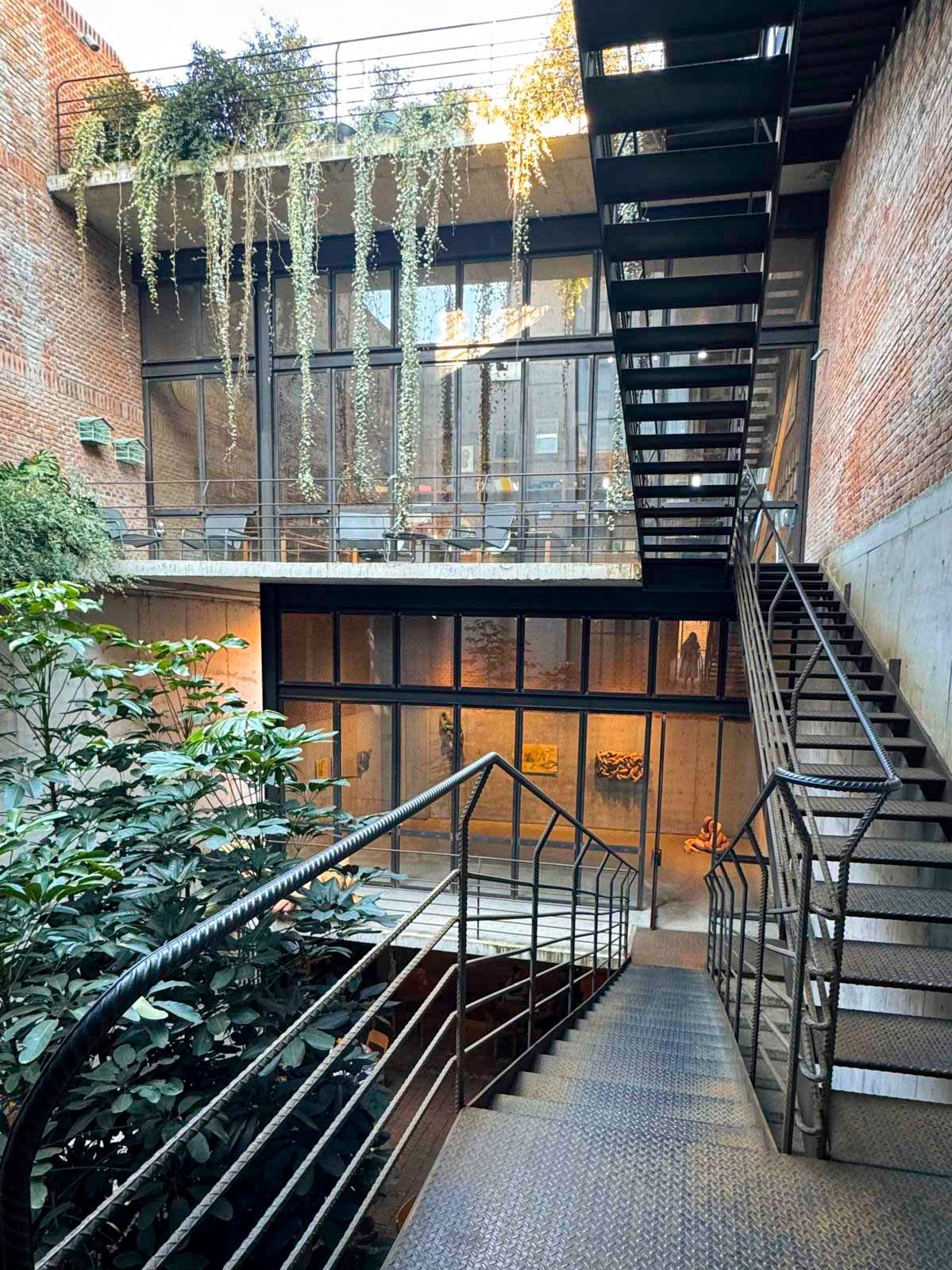 A red building with a spiral staircase is seen through a window