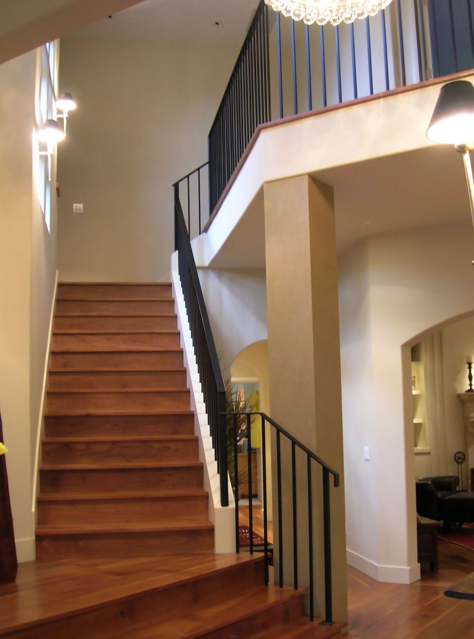 A wooden staircase in a house with a black railing
