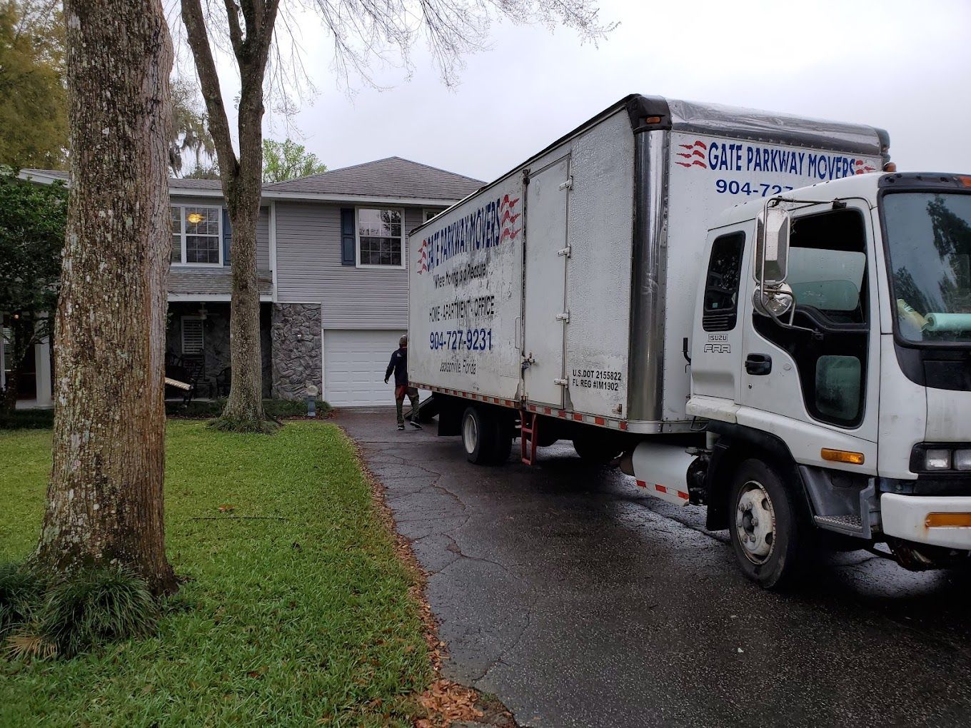 A man is loading boxes into a moving truck in front of a house.