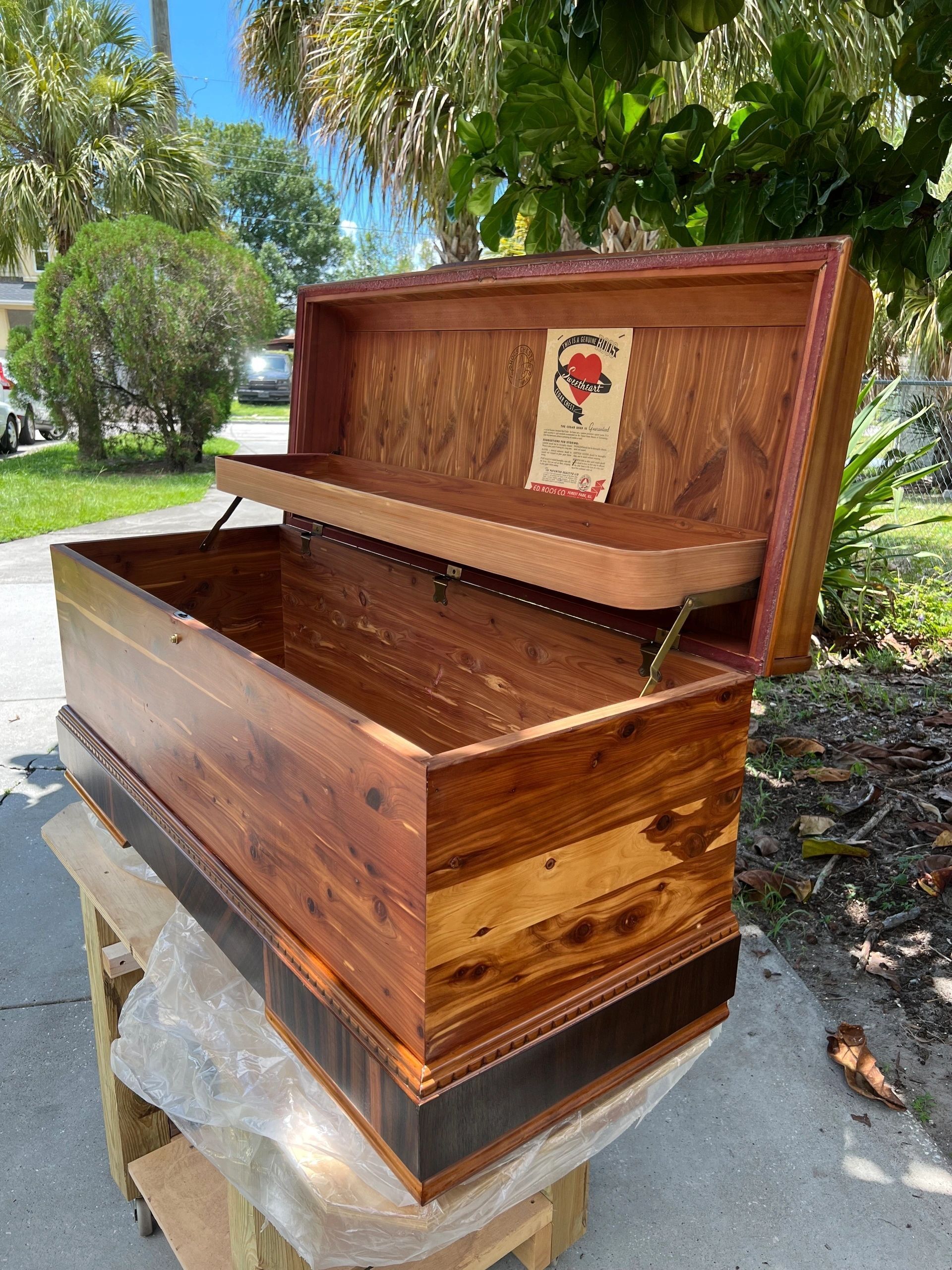 Open wooden tool chest with a raised tray. Brown wood, outdoors.