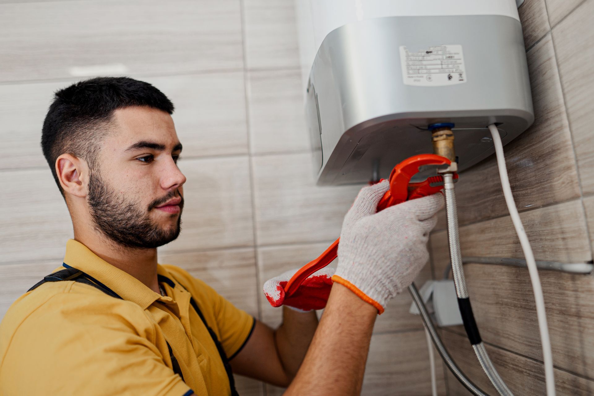 A technician installing a water heater with wrench, highlighting professional water heater install.