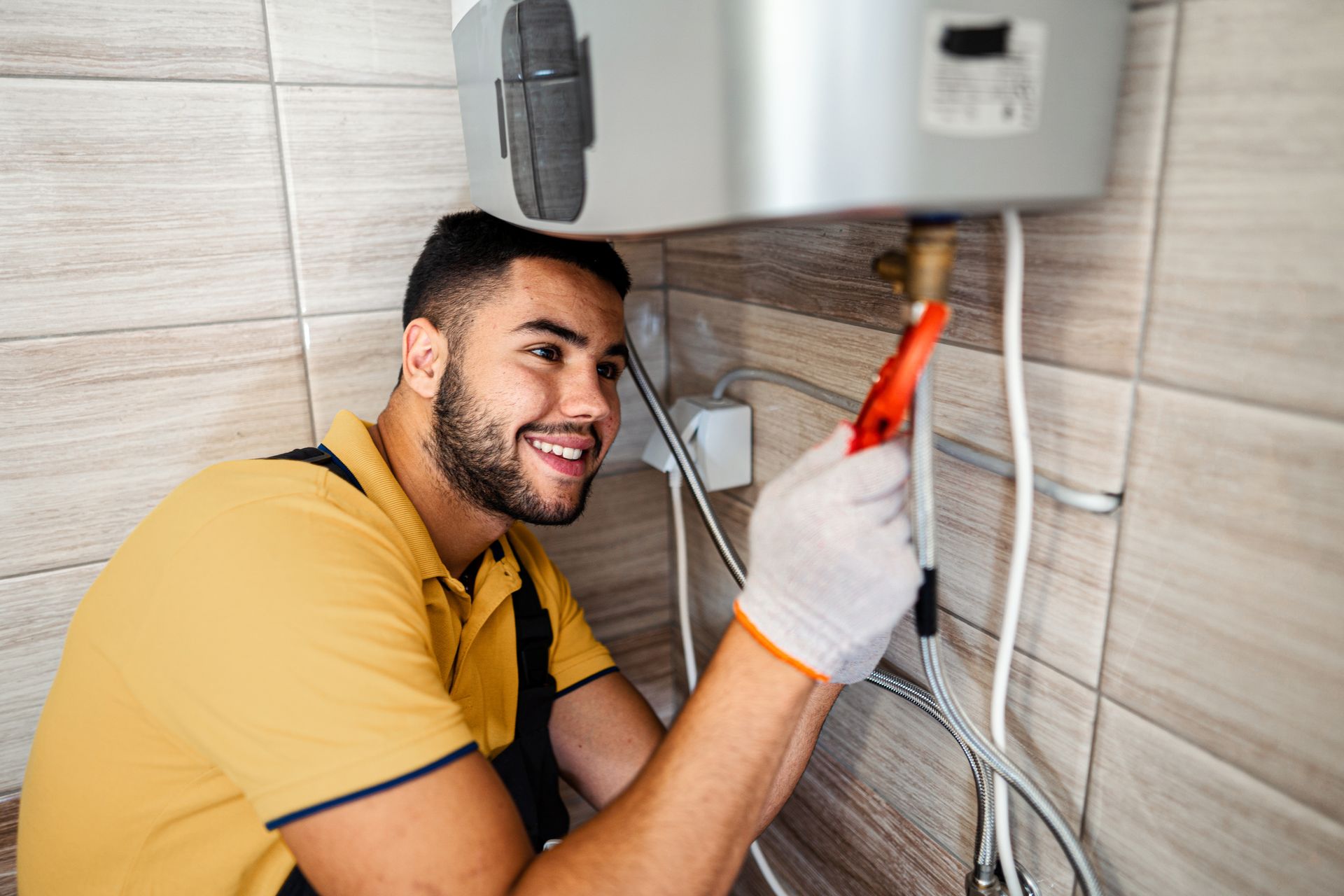 Smiling plumber adjusts a water heater with a wrench, showcasing professional water heater install. Smiling plumber adjusts a water heater with a wrench, showcasing professional water heater install.