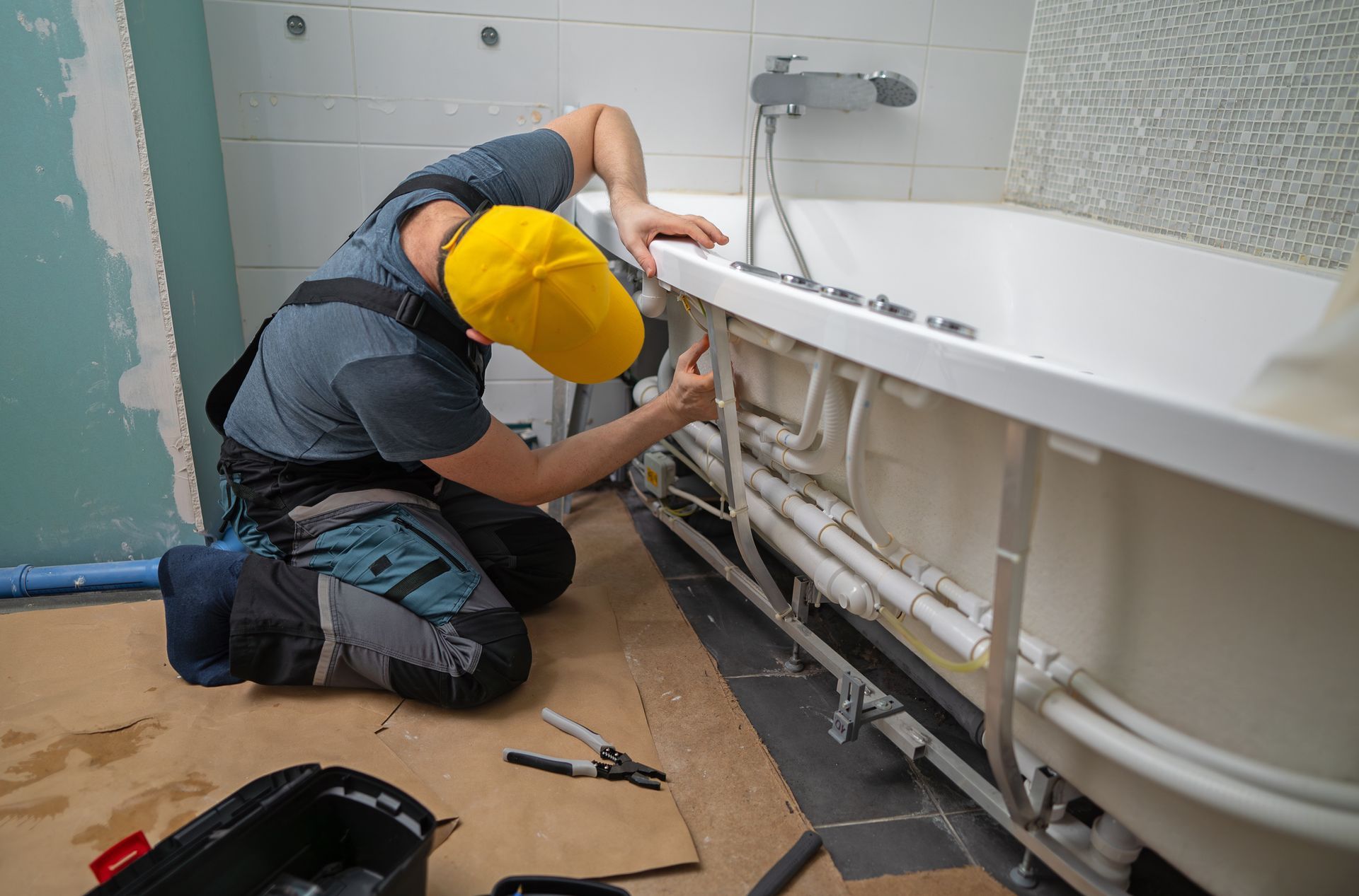 A man servicing the pipe system of a bathtub.