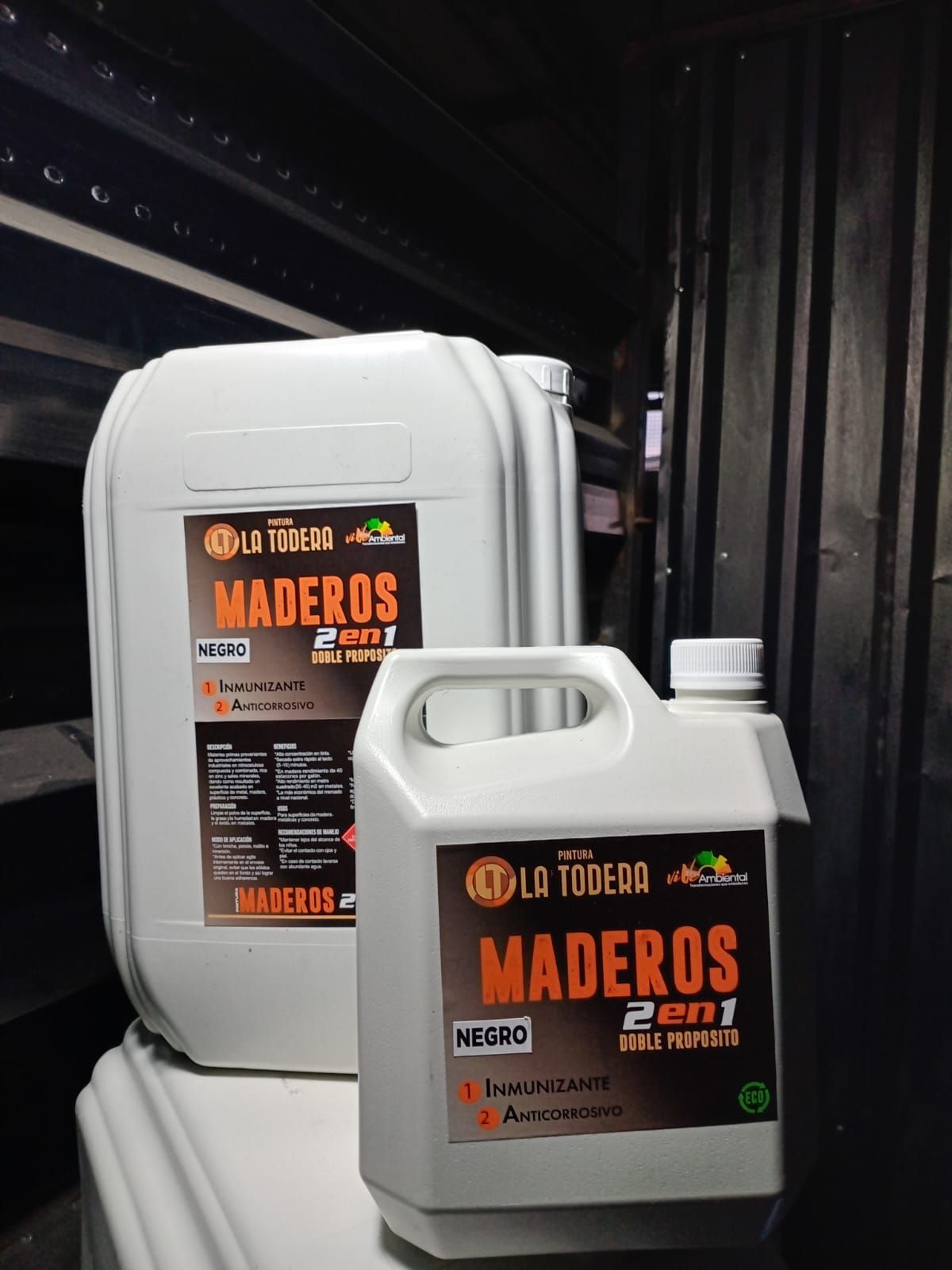Dos contenedores blancos de tratamiento de madera “Maderos 2 en 1”, con etiquetas en color naranja oscuro y negro.