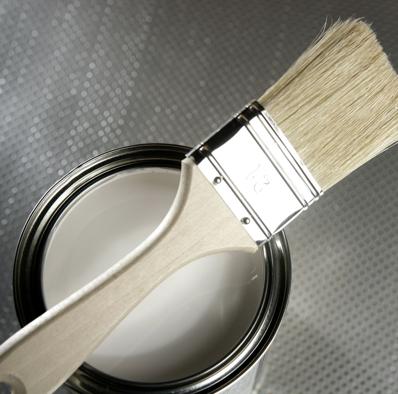 Pincel apoyado sobre una lata de pintura blanca; toma de primer plano.
