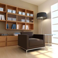 Acogedora sala de estar con sillón de cuero marrón, estanterías de madera y lámpara de pie cerca de una ventana luminosa.