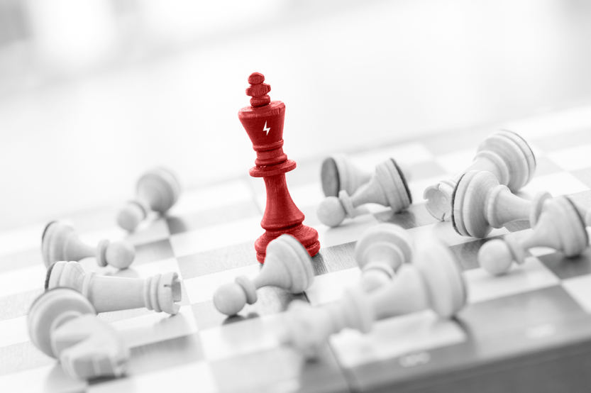 Peça vermelha do rei no xadrez, vitoriosa sobre as peças brancas derrotadas. Tabuleiro de xadrez.