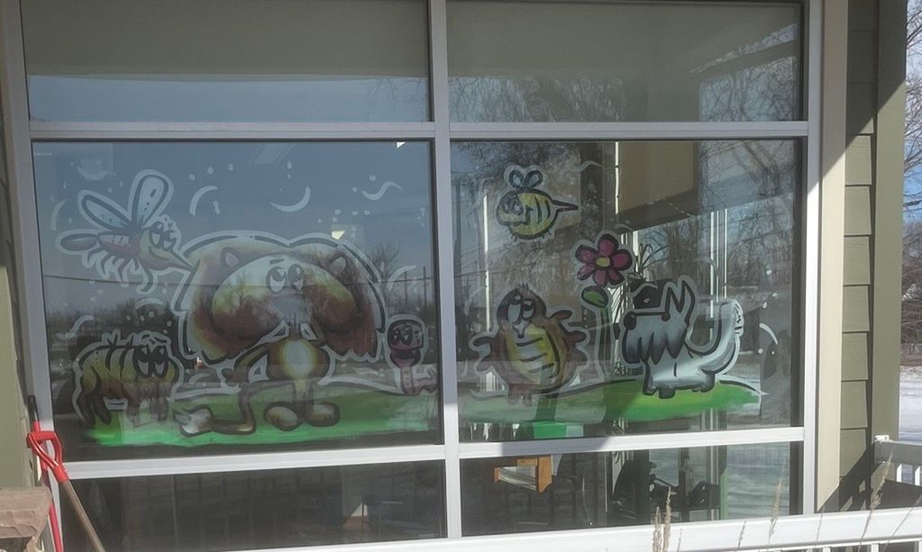 A window with a drawing of a cow and a bee on it.