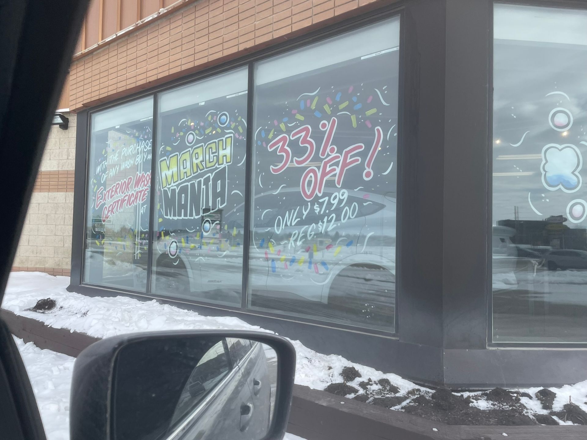 A car is driving past a store with a sign on the window that says 33 % off.